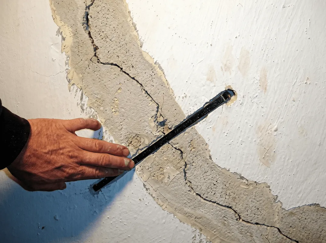 A wall with a large crack is being inspected by a professional in Ogden, UT
